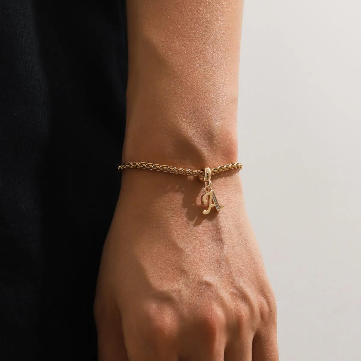 Gold initial charm bracelet with letter A worn on wrist